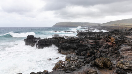 Wellen peitschen gegen das vulkanische Gestein der Küste bei Vinapu auf Rapa Nui, Osterinsel