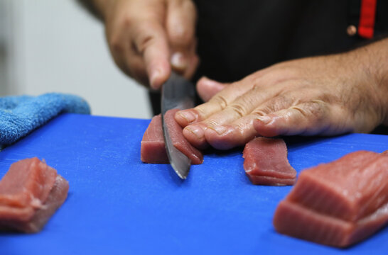 chef profesional de sushi cortando atún rojo para elaboración