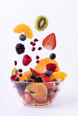 the fresh fruit mixed into pieces falls into the glass bowl. White background
