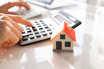 Person Hand Calculating A Real Estate Property