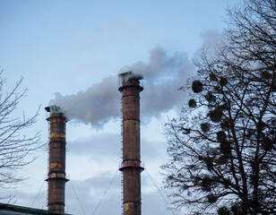 two idustrial pipes with smoke on blue sky background. Air industrial pollution