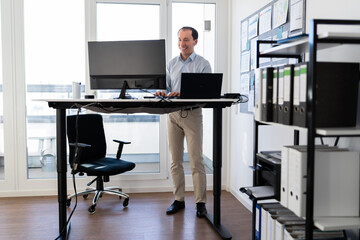Man Using Adjustable Height Standing Desk In Office