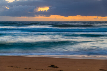Sunrise at the seaside with waves and clouds