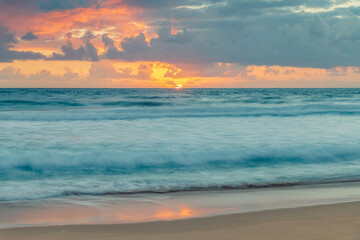 Sunrise at the seaside with waves and clouds
