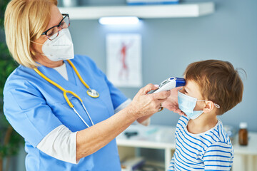 Pediatrician doctor examining little kids in clinic temperature check