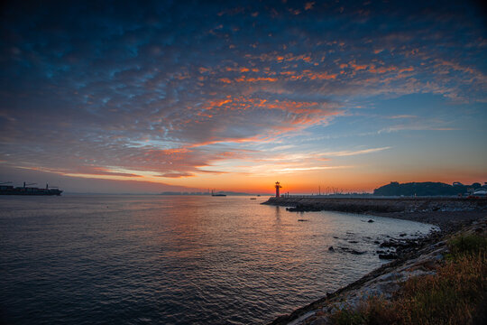 A harbor in the dawn sky with a lighthouse visible
