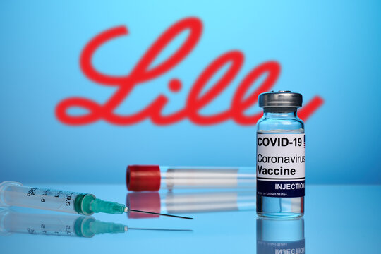 Krasnoyarsk, Russia - April 29, 2021: Eli Lilly Covid vaccine and syringe - photo on a blue gradient background. True vaccine against coronavirus infection. Blurred Eli Lilly company logo.
