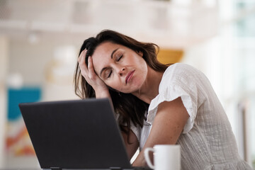 sad depressed remote working brown hair woman sitting disappointed with headache infront of a...