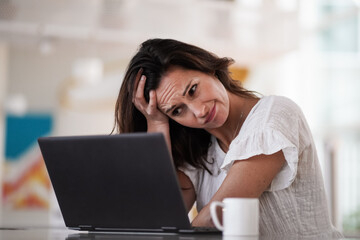 sad depressed remote working brown hair woman sitting disappointed with headache infront of a...