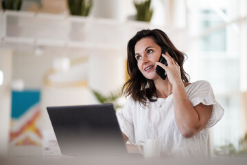 remote working dark haired woman calling and chatting infront of a laptop or notebook in casual...