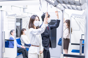 マスクをして電車移動をする若い女性
