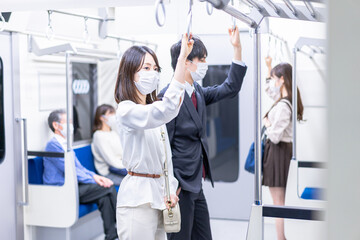Fototapeta na wymiar マスクをして電車移動をする若い女性