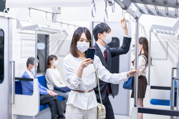 Fototapeta na wymiar マスクをして電車移動をする若い女性