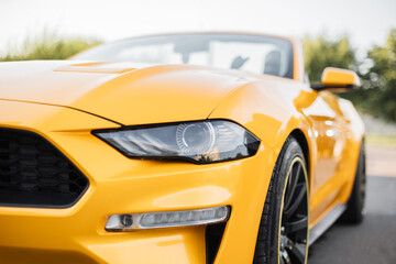 Particle view of yellow brand new modern luxury sport car parked outdoors. Headlights and hood of...
