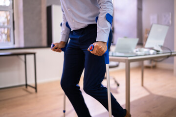 Worker With Crutches At Workplace Or Office