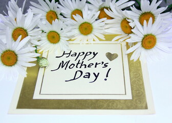 Happy Mother’s Day. A bouquet of daisy flowers with a card that says "Happy Mother's Day" hand written in black.     