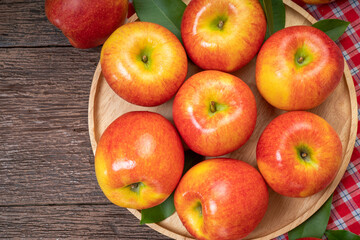 Red apple in wooden plate on wooden background, US. Red Envy apple on wooden table.