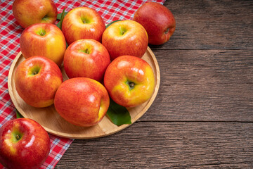 Red apple in wooden plate on wooden background, US. Red Envy apple on wooden table.