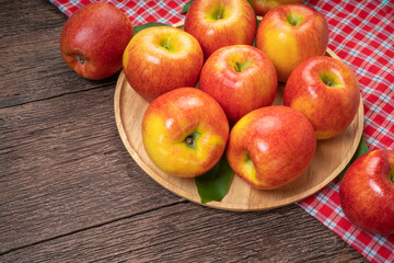 Red apple in wooden plate on wooden background, US. Red Envy apple on wooden table.