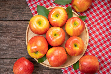 Red apple in wooden plate on wooden background, US. Red Envy apple on wooden table.