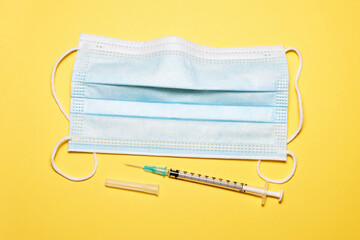 Top down view of Mask and syringe on Yellow background, Concept of virus protection.
