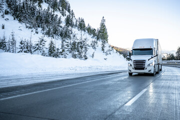 Bonnet big rig white semi truck transporting cargo in dry van semi trailer running on the winter...