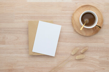 Obraz na płótnie Canvas Blank paper cards, Blank greeting card invitation Mockup with Dried Bunny Tail grass and coffee cup on wood table, wood desk background, Minimal wood table workplace composition, flat lay, mockup