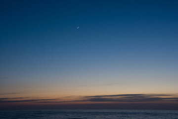 静かな海の夕暮れと三日月
