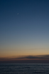 静かな海の夕暮れと三日月
