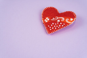 Top view Valentine's Day concept with copy space. Red textile heart on purple papper background