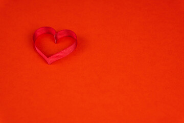 Valentine's Day or birthday concept with copy space. Red ribbon heart on red papper