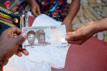 African hands exchanging cash, money or the Nigerian currency know as Naira in a tailoring shop for...