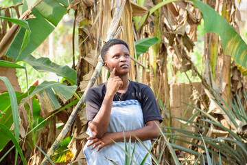An African female farmer, business woman or entrepreneur standing on a farm land and thinking of something