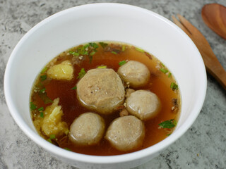 beef meatballs in a white bowl with a wooden spoon and fork