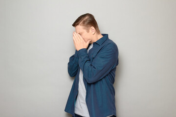 Portrait of unhappy mature man covering face with hands