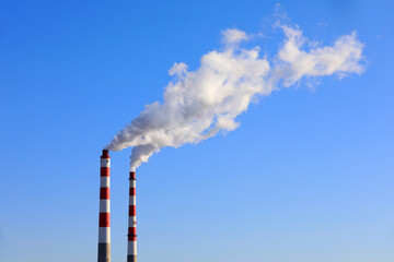 The chimney that emits smoke and dust in the blue sky