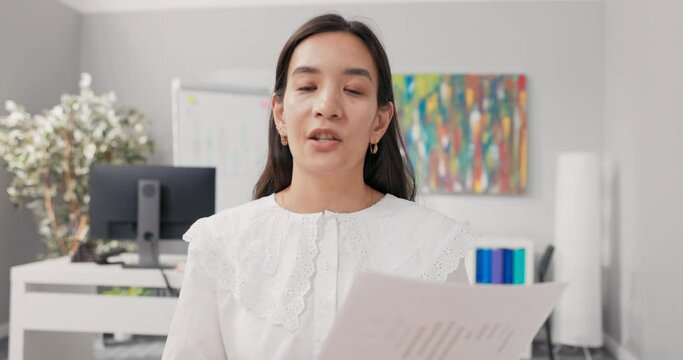 A hardworking corporate accountant sits in an office having a video conversation with the head of the corporation, inquiring about contract details, holding up documents, pointing to them