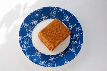 a piece of honey cake on a blue and white plate, top view