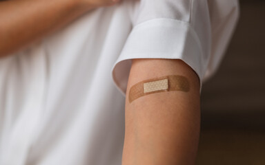 Closeup image of a woman with adhesive bandage, medical plaster, band aid on her arm