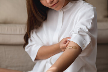 Closeup image of a young woman with adhesive bandage, medical plaster, band aid on her arm
