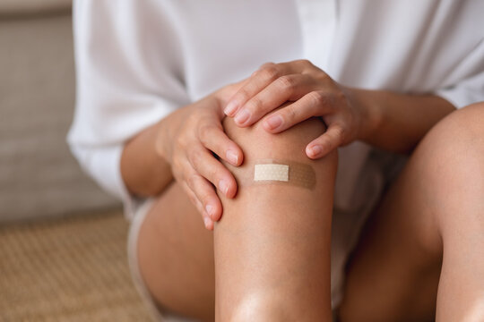 Closeup image of a young woman with adhesive bandage, medical plaster, band aid on her knee