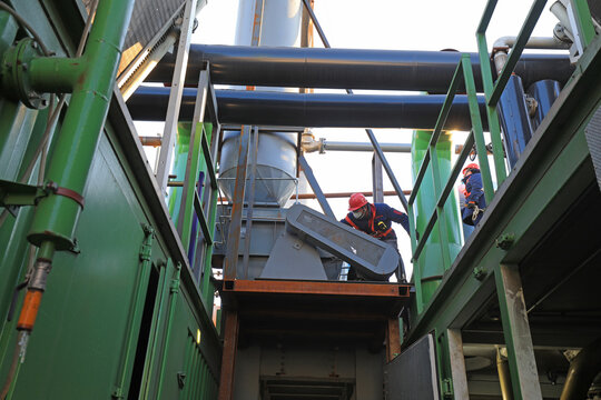 Workers are adjusting the external equipment of biogas generator in a biogas power station, North China