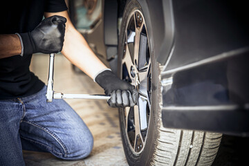 Car mechanic checking and use a wrench to change the tire. Concept of car care service maintenance and safety.