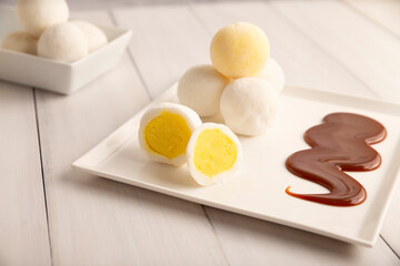 Ice cream mini Mochi with caramel (cajeta). Traditional Japanese dessert made from rice flour. Close up on white wooden surface.