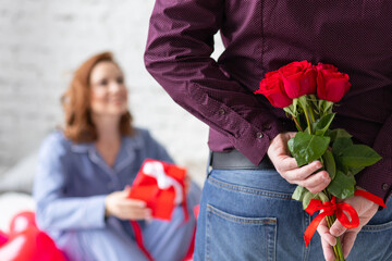 Happy couple on Saint Valentine's Day morning. Man making surprise. Woman smiling