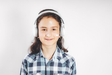 Portrait of a positive smiling teenage girl. Cute pretty girl in white headphones on a white background. Copy space. Teenager stock photo