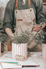 Florist make gift bouquets in hat boxes. Graceful female hands make a beautiful bouquet. Florist workplace. Small business concept. Vertical shot