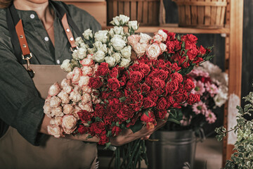 Woman florist hands holding a big bouquet of roses. Florist workplace. Small business concept. Flowers and accessories shop. Close-up