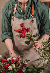 Florist make gift bouquets. Graceful female hands make a beautiful bouquet. Florist workplace. Small business concept. Flowers and accessories. Vertical shot