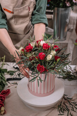Florist make gift bouquets in hat boxes. Graceful female hands make a beautiful bouquet. Florist workplace. Small business concept. Flowers and accessories. Vertical shot